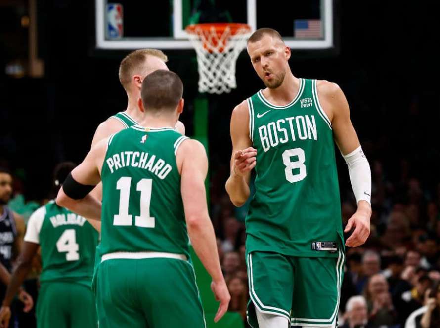 Kristaps Porzingis #8 of the Boston Celtics points at Payton Pritchard #11 after Pritchard hit a three point basket during the second half against the Sacramento Kings at TD Garden on April 5, 2024 in Boston, Massachusetts.