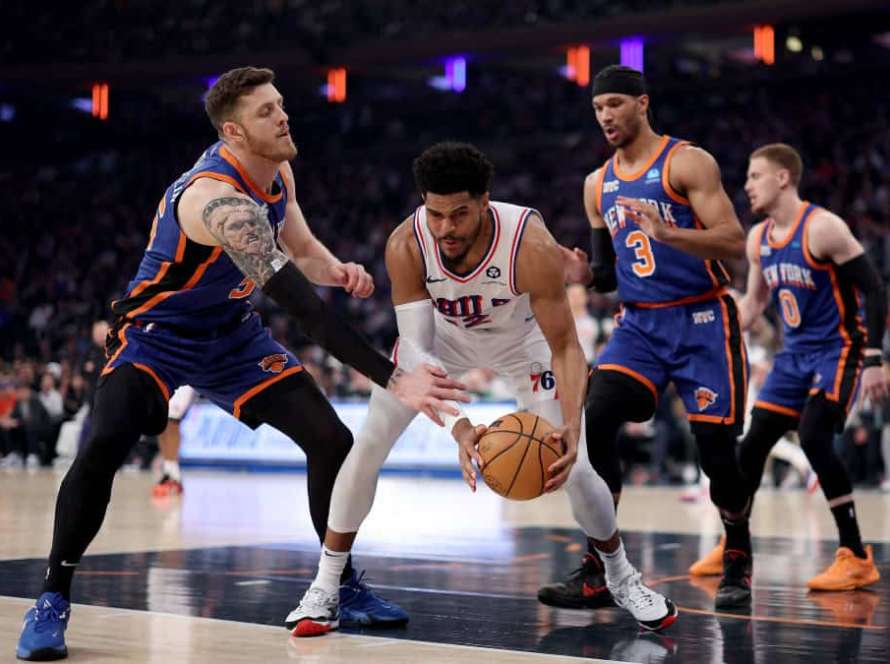 Tobias Harris #12 of the Philadelphia 76ers grabs the loose ball as Isaiah Hartenstein #55 and Josh Hart #3 of the New York Knicks defend during the first half at Madison Square Garden on April 30, 2024 in New York City.