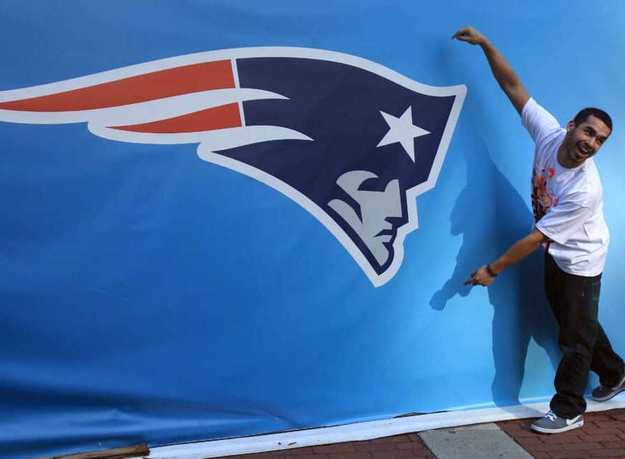 INDIANAPOLIS, IN - FEBRUARY 01: A fan poses for a photo next to a giant New England Patriots logo prior to Super Bowl XLVI between the New York Giants and the New England Patriots on February 1, 2012 in Indianapolis, Indiana.
